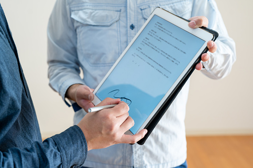 Japanese man signing digital contract on tablet, close-up